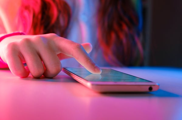 Phone on the table with a person's pointer finger on the surface